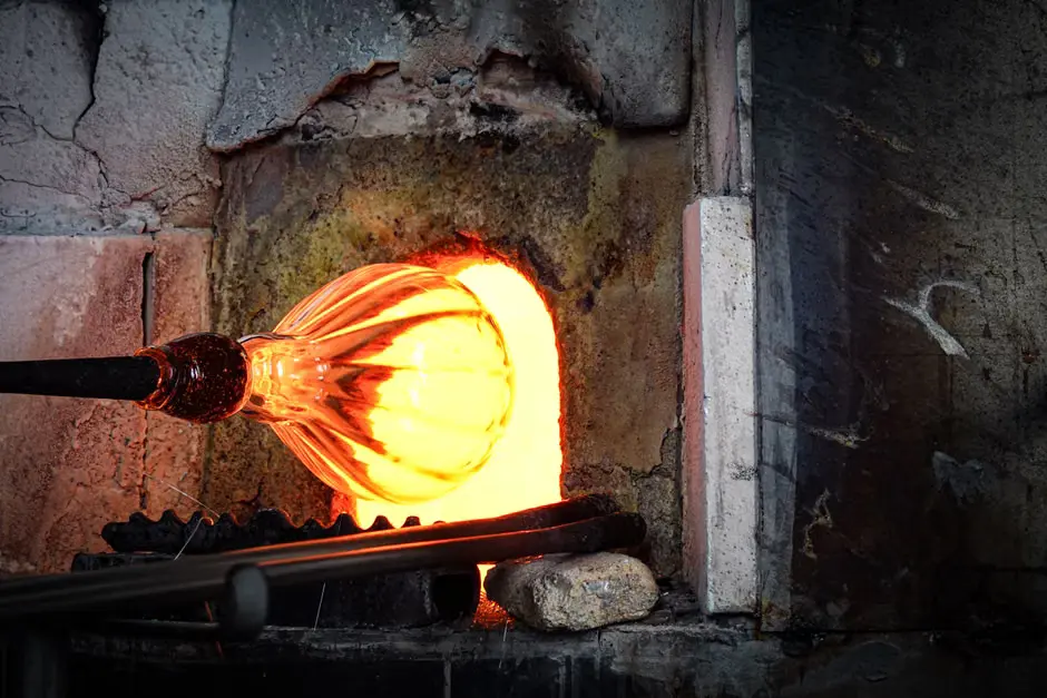 a glass maker inserting murano glass into furnace